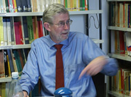 Prof. Dr. Hans Jürgen Schlösser sitzt vor einem Bücherregal